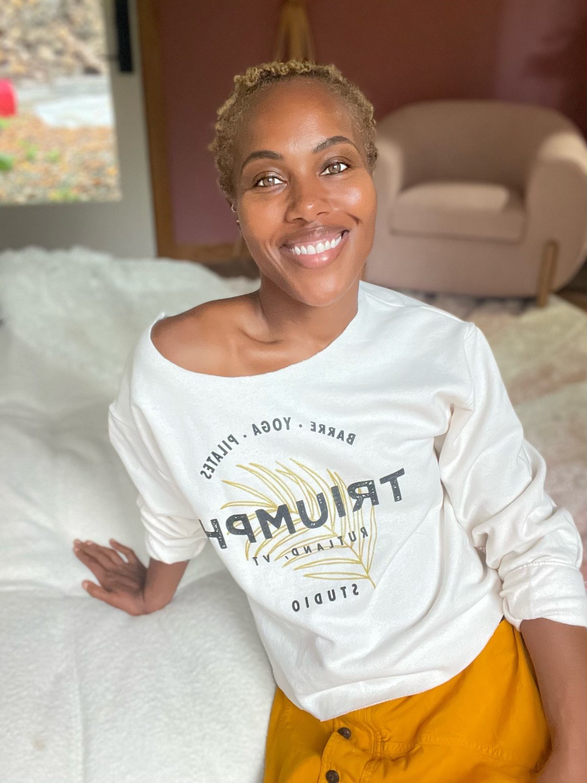 A smiling woman wearing a Triumph Studio sweatshirt